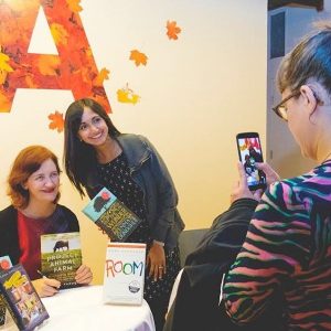 A person taking a iphone picture of Emma Donoghue and a fan