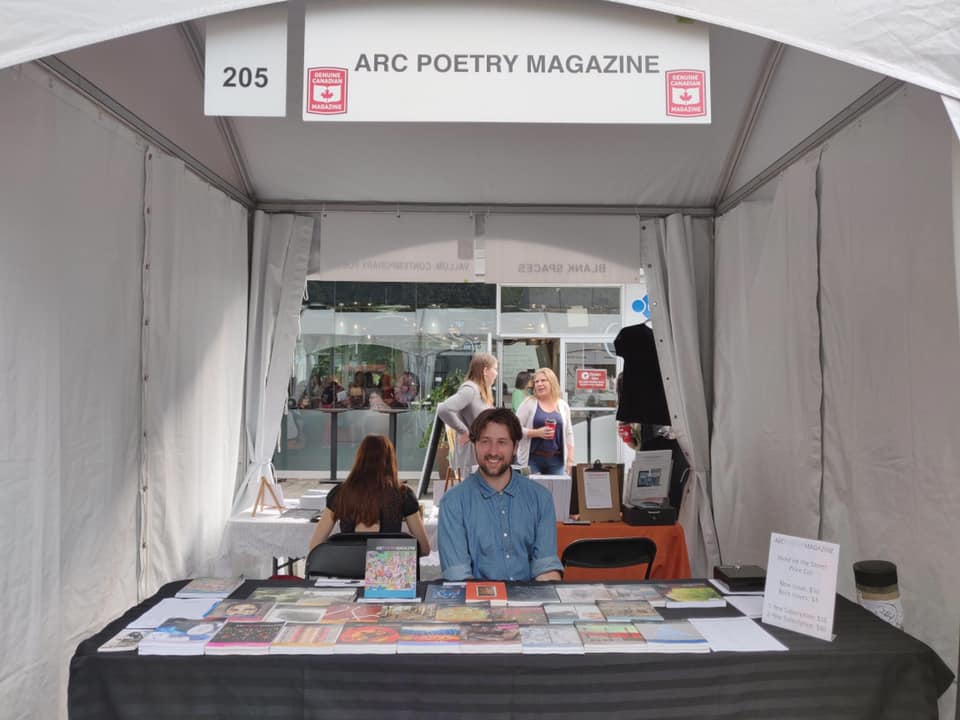 Arc Poetry Magazine stand with person sitting behind table with book display