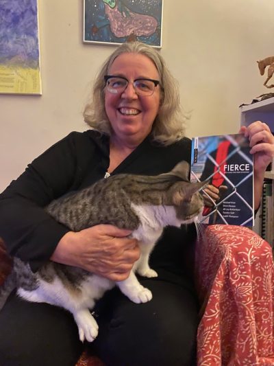 A photograph of a older person holding a cat and a book