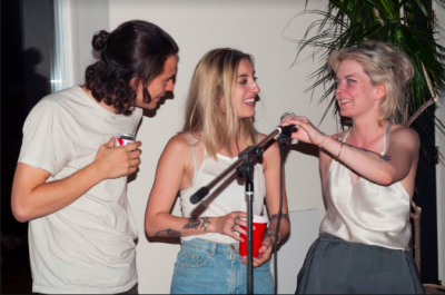 Three people at a mic smiling and laughing