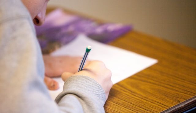 A young person holds a pencil to paper