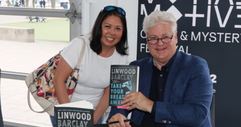 Linwood Barclay at a 2022 book signing with a fan. He is holding up his book Take Your Breathe Away