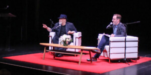 Walter Mosely on stage with Roland Gulliver during MOTIVE 2024. Walter is pointing out into the audience